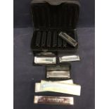 A collection of mixed sized harmonicas, cased and uncased.