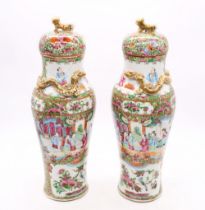 A pair of late 19th century small Cantonese famille rose vases and cover, decorated with figural,