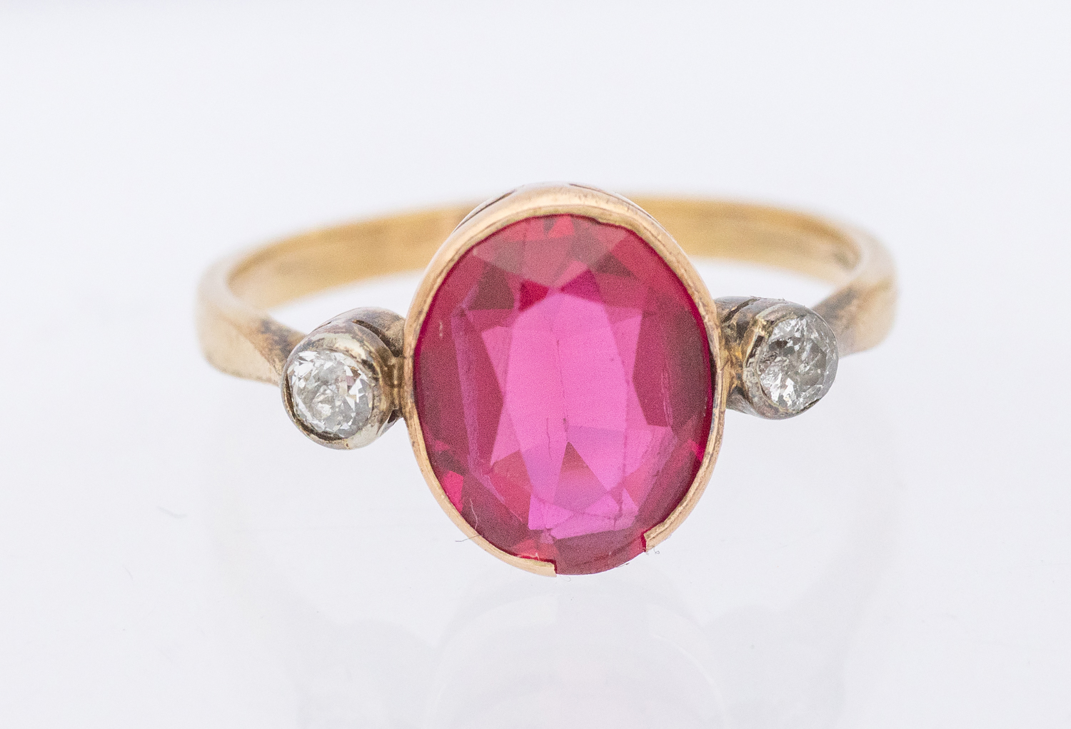 A synthetic ruby and diamond three stone 9ct gold ring, set with an oval ruby approx 9x7mm, single