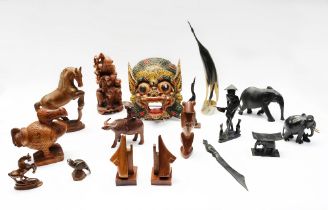 A collection of Chinese and Eastern treen carved figures, masks and ebony elephants.