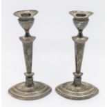 A pair of George V silver candlesticks, urn shaped removable sconces over a tapered body and oval