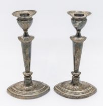 A pair of George V silver candlesticks, urn shaped removable sconces over a tapered body and oval