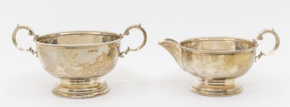 A matching George V silver milk jug and sugar bowl, both with beaded edging and circular footed