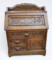 A carved solid oak late 19th Century/early 20th Century bureau with carved gallery top drop down