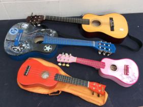 Two childrens guitars along with two other smaller instruments.