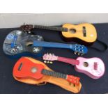 Two childrens guitars along with two other smaller instruments.