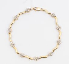 A diamond set 10ct gold bracelet, comprising alternate wave like gold links and grain set diamond