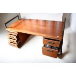 A 20th Century teak office desk with file and paper/stationery either side, metal supports, a/f