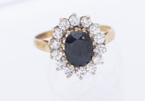 A sapphire and cz 9ct gold cluster ring,  set with an oval mixed cut sapphire within a white stone