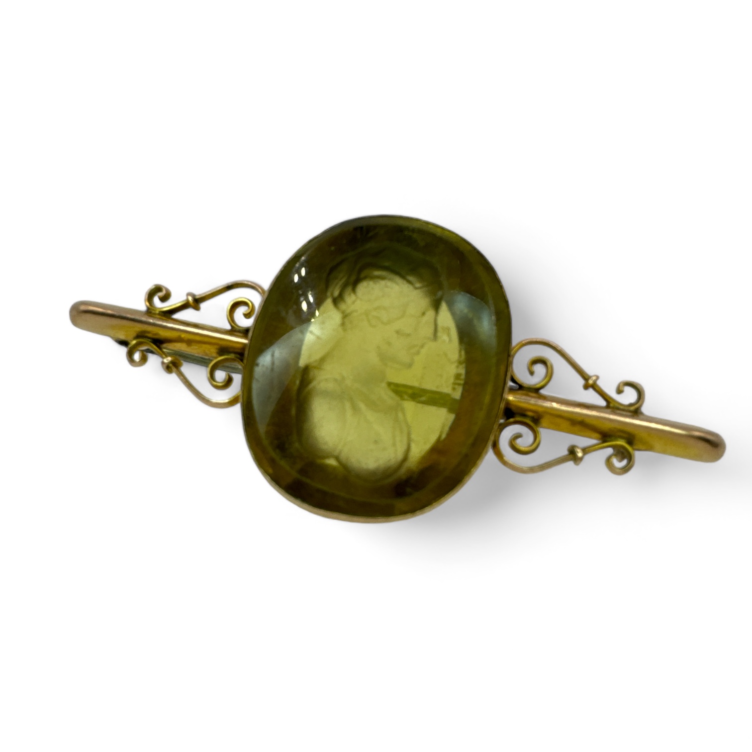 An antique glass intaglio in a "9c" stamped brooch mount. The greenish-yellow moulded gem features a