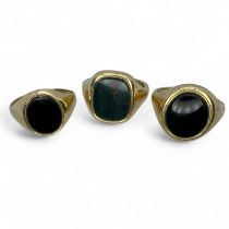 Three 9ct gold gentleman's signet rings. Comprising a bloodstone set ring, size W; an onyx set ring,
