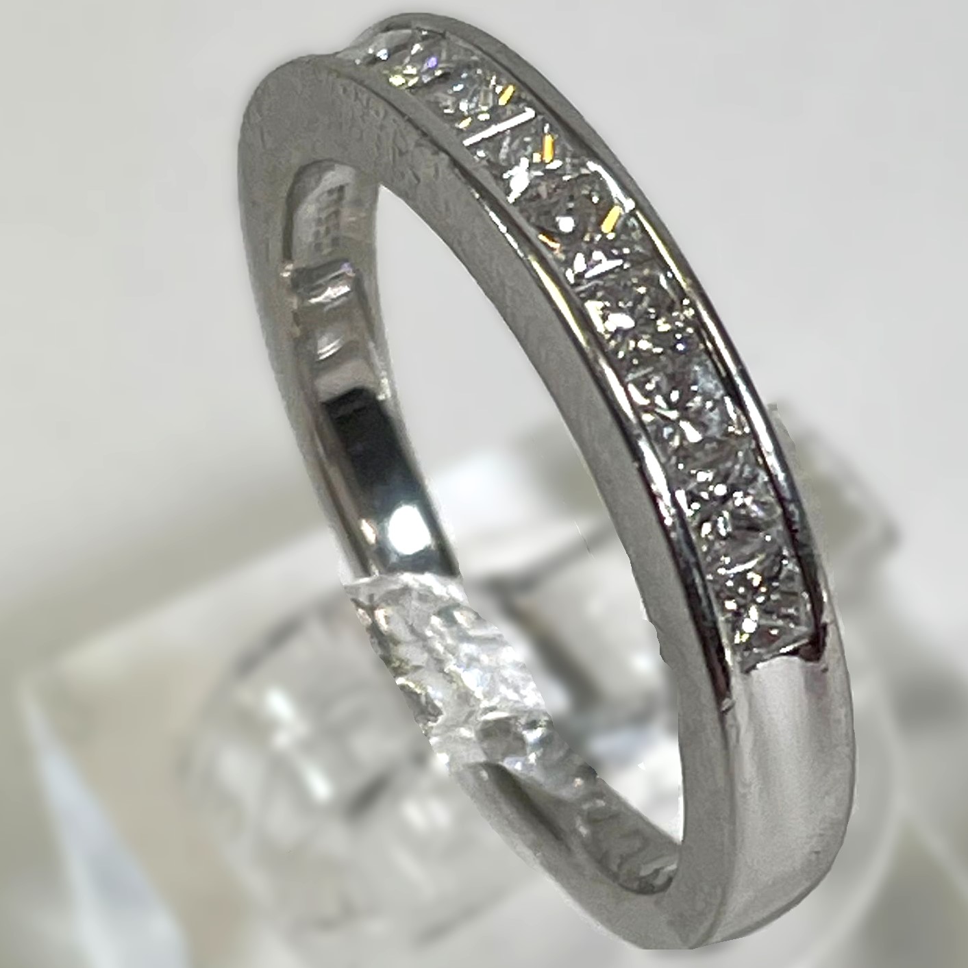 A 950 Platinum channel set diamond half eternity ring. Set with nine princess cut diamonds,