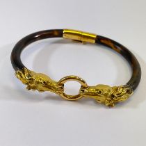 A high grade yellow gold double horsehead Tortoiseshell hinged bangle. One side of the bangle is