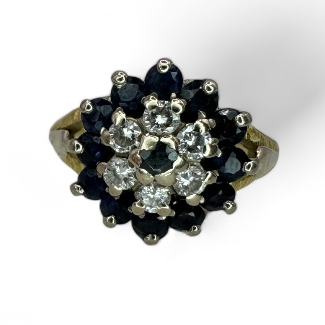 A sapphire and diamond target cluster ring. Set into yellow precious metal testing as 14K gold.