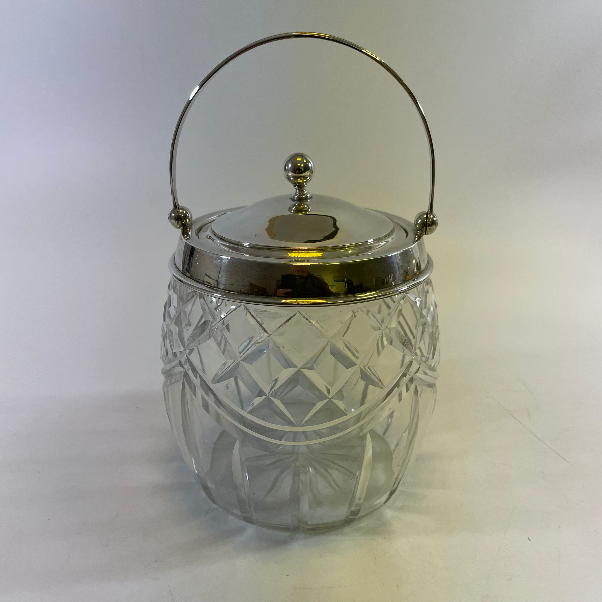 A cut glass biscuit barrel with a silver top, hallmarked Birmingham 1930/31. Approximately 13cm wide