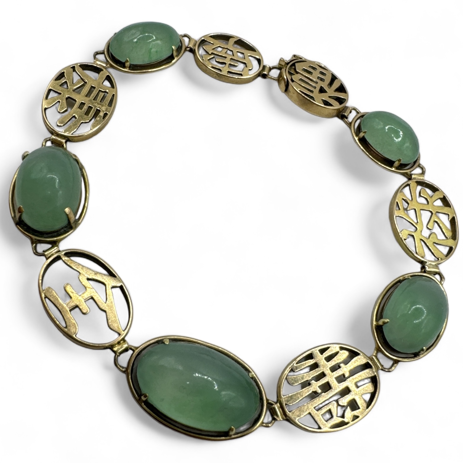 A translucent green jadeite set bracelet, featuring Chinese characters. Stamped "14k" and testing