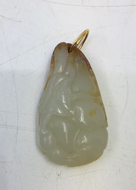 A Chinese carved celadon jade pendant with russet inclusions