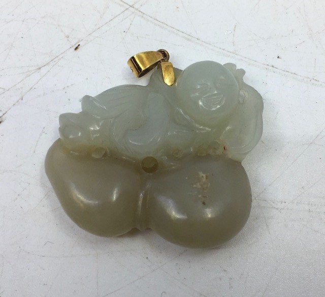 A Chinese carved jade pendant depicting peaches