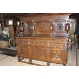 A very large victorian dresser having a raised panel back with the letters J & S carved scroll and