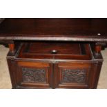Dark oak monks hall bench with hinged top arms over hinged chest base with floral carving on bun