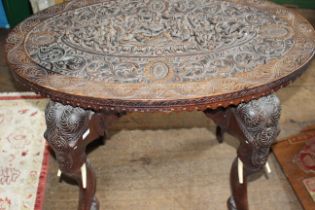 An Indian carved occasional table, the oval top with relief carved central section on elephant