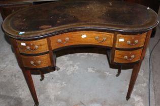 An Edwardian Kidney shape mahogany inlaid desk raised on brass castors. 97cm wide. (1) new leather