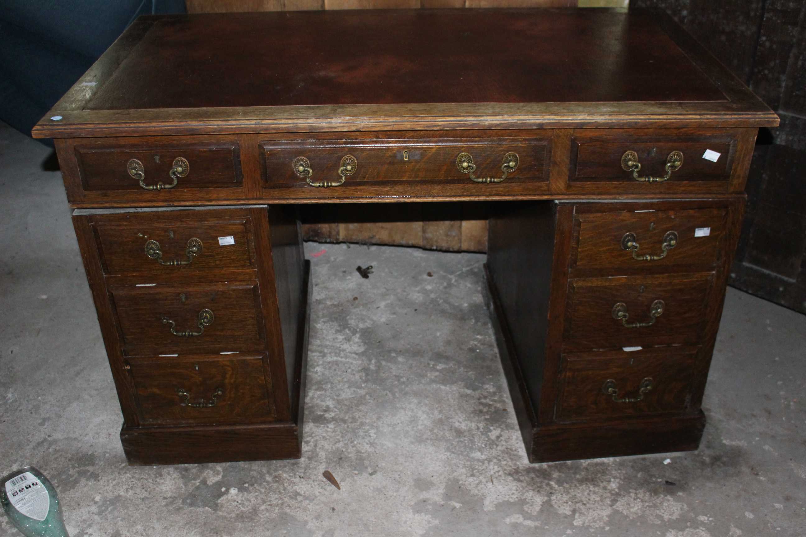An antique twin pedestal oak desk with red leather top and brass handles. 122cm wide and 69cm