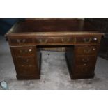 An antique twin pedestal oak desk with red leather top and brass handles. 122cm wide and 69cm
