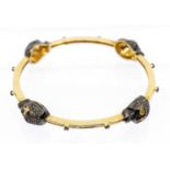 A diamond set silver gilt bangle, comprising four brown diamond set skull motifs, black rhodium