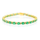 An emerald and diamond 18ct yellow gold tennis bracelet, comprising alternating oval mixed cut