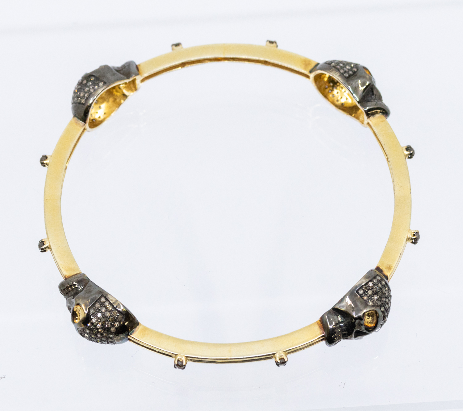 A diamond set silver gilt bangle, comprising four brown diamond set skull motifs, black rhodium - Image 2 of 4