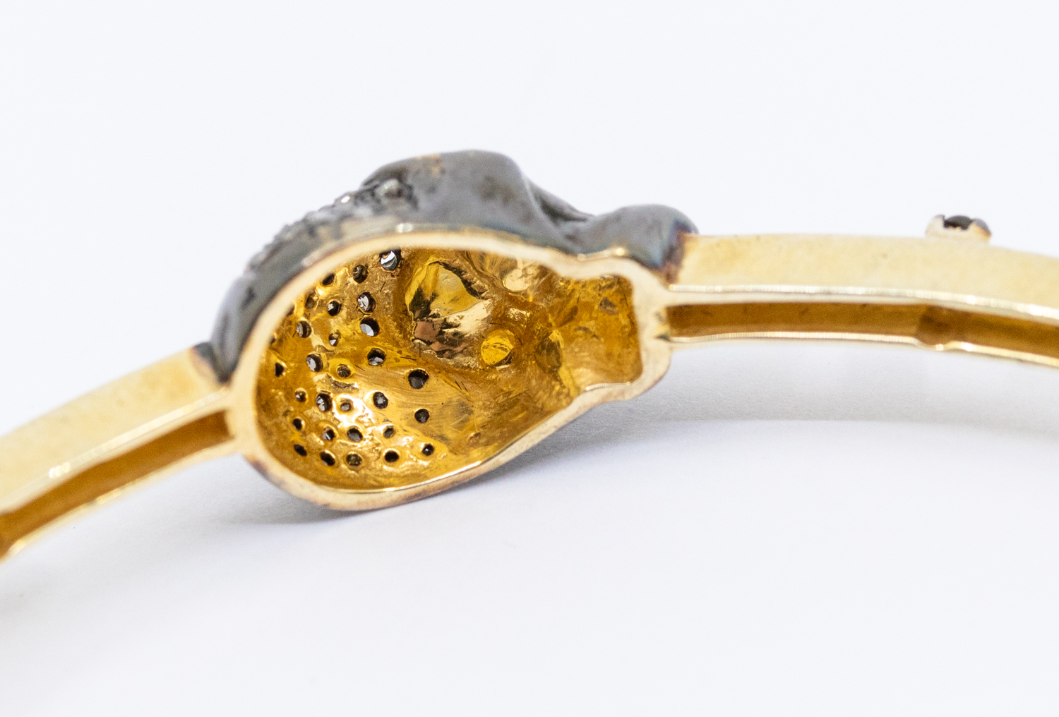 A diamond set silver gilt bangle, comprising four brown diamond set skull motifs, black rhodium - Image 4 of 4