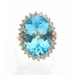 A blue topaz and diamond set 18ct gold cocktail ring, comprising an oval mixed cut blue topaz (Swiss