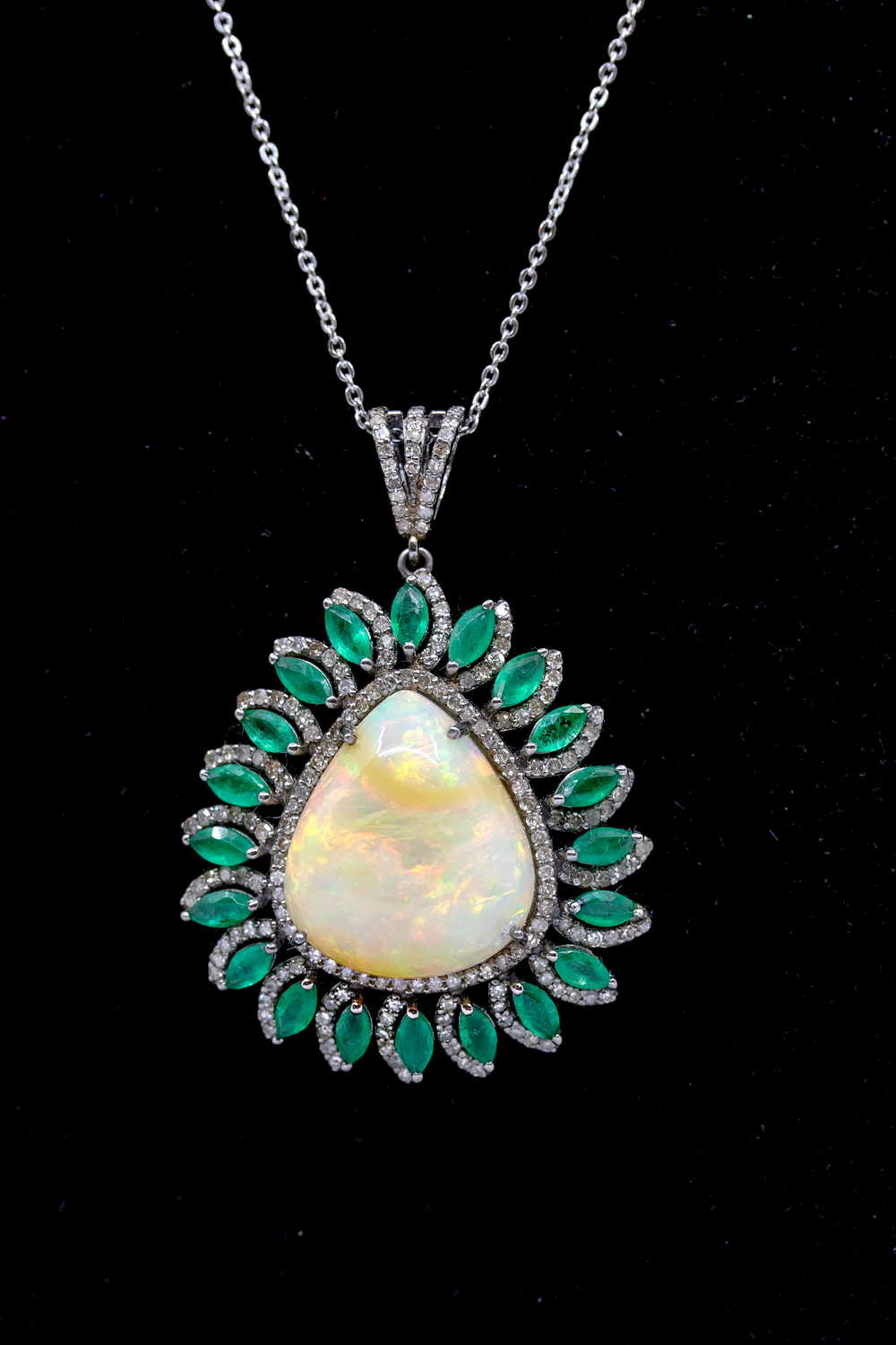 A large opal, emerald and diamond set pearl shaped silver pendant, comprising a pearl shaped opal to