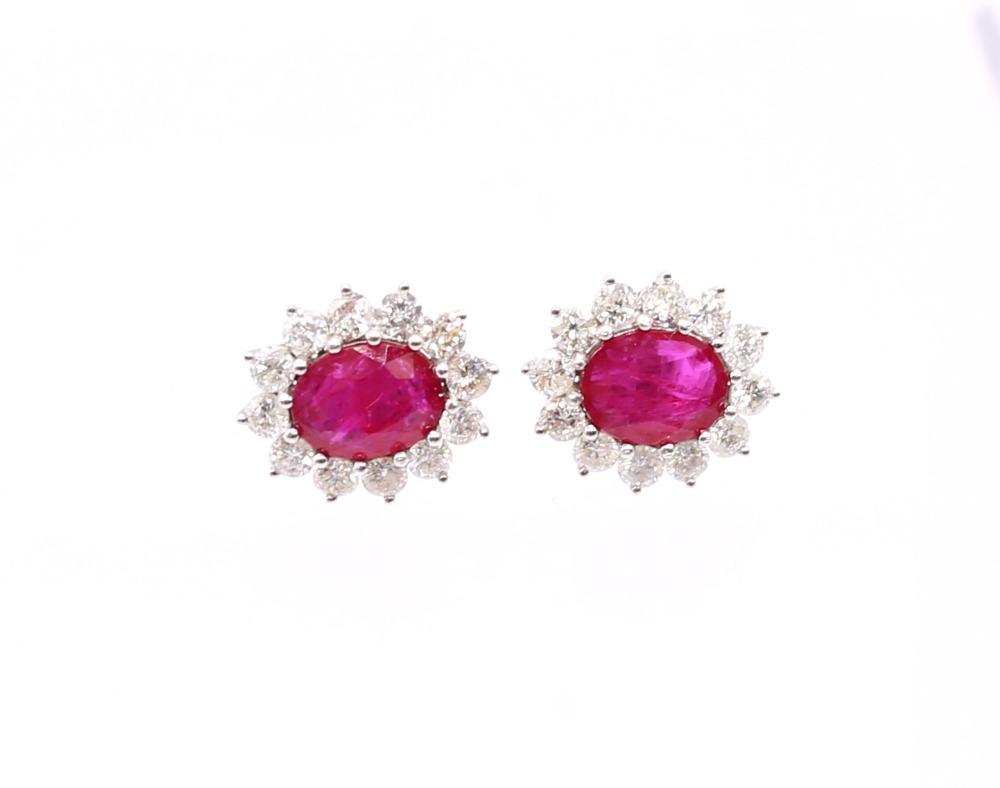 A pair of ruby and diamond set 18ct white gold oval cluster studs, rubies weighing a total of approx