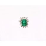 A Zambian emerald and diamond 18ct gold cluster ring, comprising a step-cut emerald (heavily
