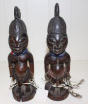 Two African carved wood Yoruba Ibeji male figures with beads and cowrie shells, 25cm high