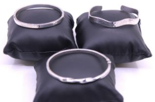 Three Sterling Silver Bangles.  To include a Silver Designer Inspired Hinged Bangle (A/F), a