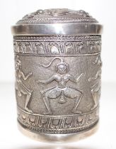 An Indian silver cylindrical box and cover repousse with dancing figures, the interior with prayer