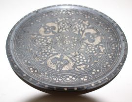 A bidri ware saucer dish with inlaid silver decoration of fish and foliage, 16.5cm diameter