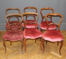 A harlequin set of six Victorian walnut balloon back chairs, raised on cabriole legs.