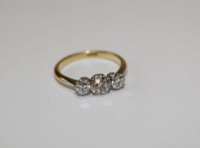 An 18ct stamped diamond three stone ring featuring three transitional round diamonds, size N.