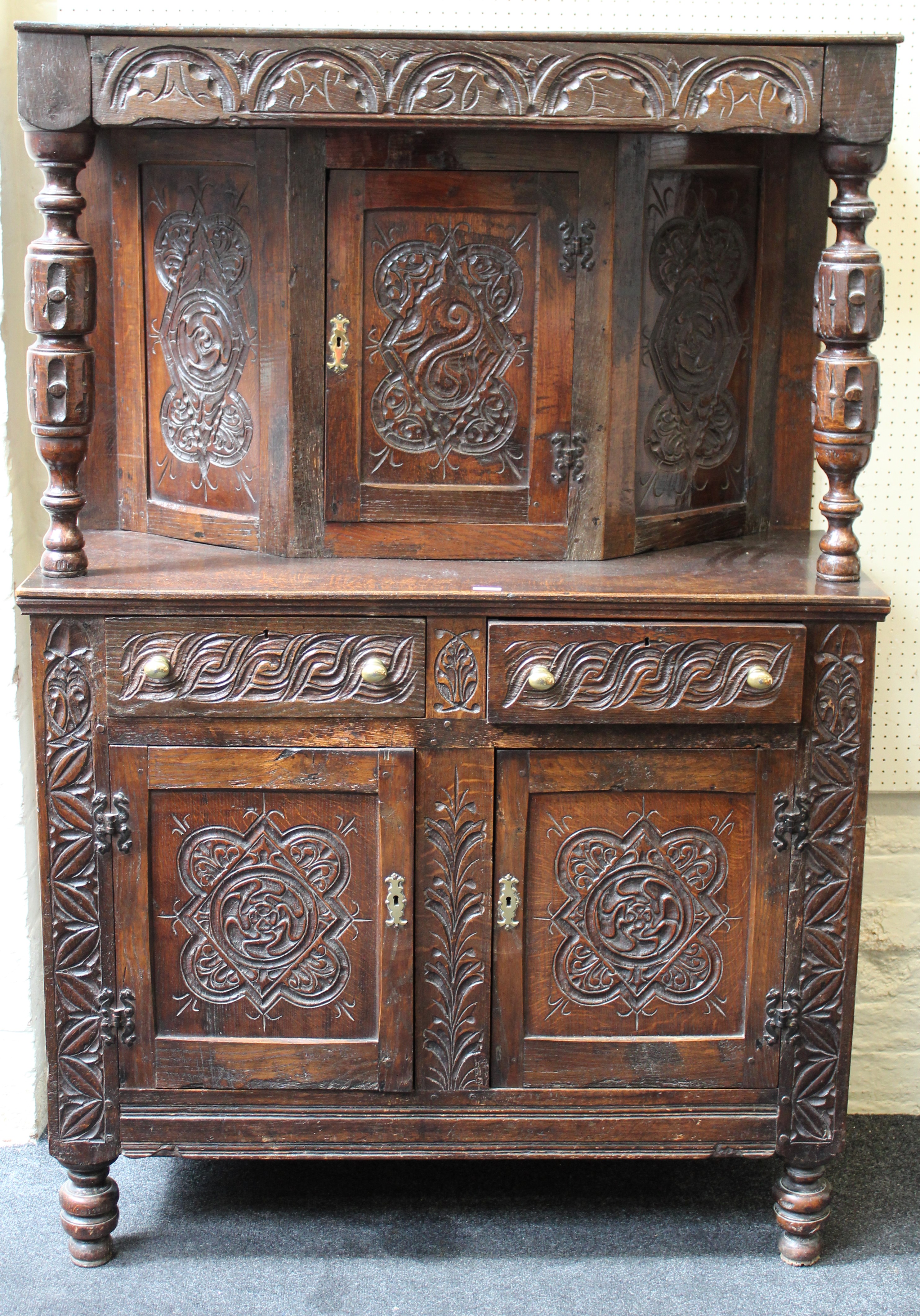 A 17th century style oak duodarn, the upper section with a cornice having pillar supports over the