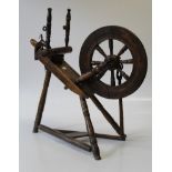 An 18th century beech spinning wheel of typical form, raised on turned legs and a triangular base,