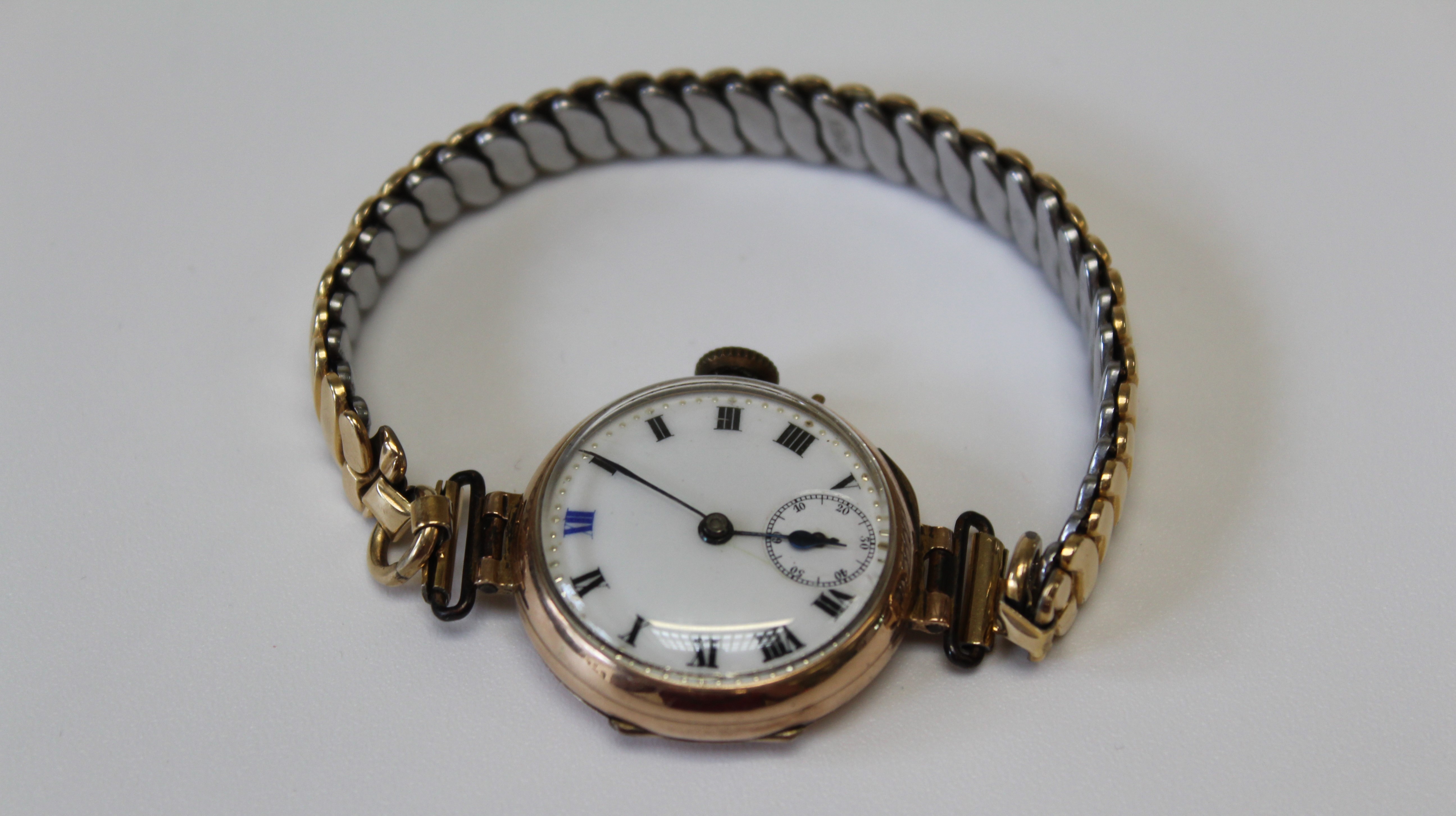 A 9ct gold cased ladies wristwatch on a gilded Gemex USA stretching bracelet. With a white enamel