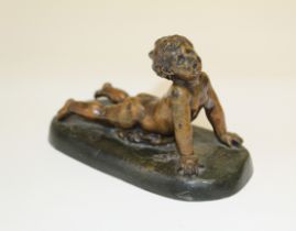 A small 20th century hollow cast bronze of a child lying prone, on an indistinctly signed
