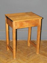 A mid 20th century beech school desk, with covered flush brass inkwell and rising top, raised on