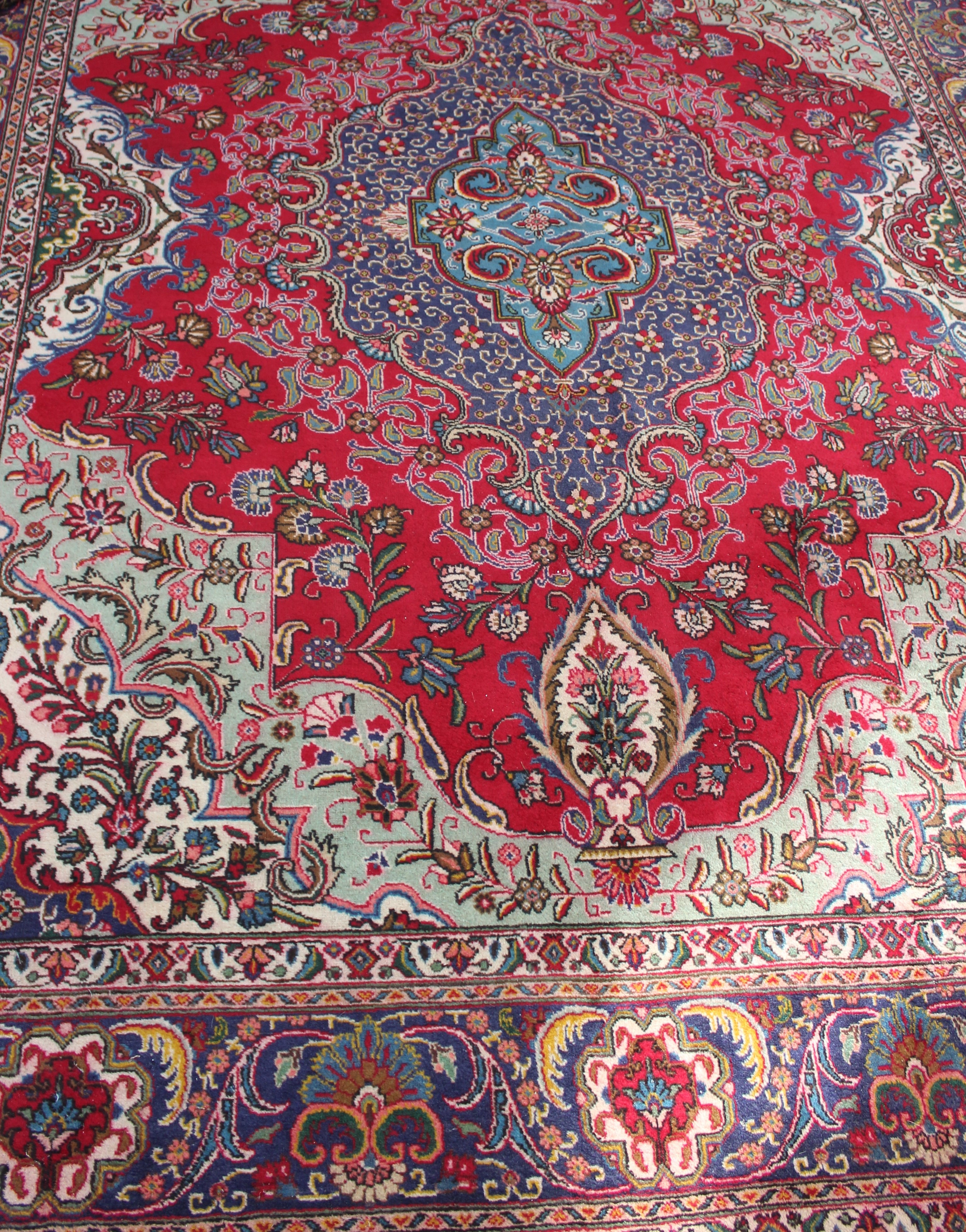 A 20th Iranian wool carpet, woven with a stepped central floral medallion on a predominantly red - Image 2 of 2