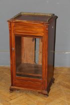 A late Victorian walnut music cabinet, with three quarter gallery top and glazed door raised on