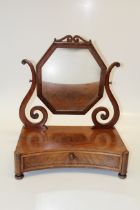 An early Victorian mahogany toilet mirror, the octagonal plate within scrolled horns, on a deep